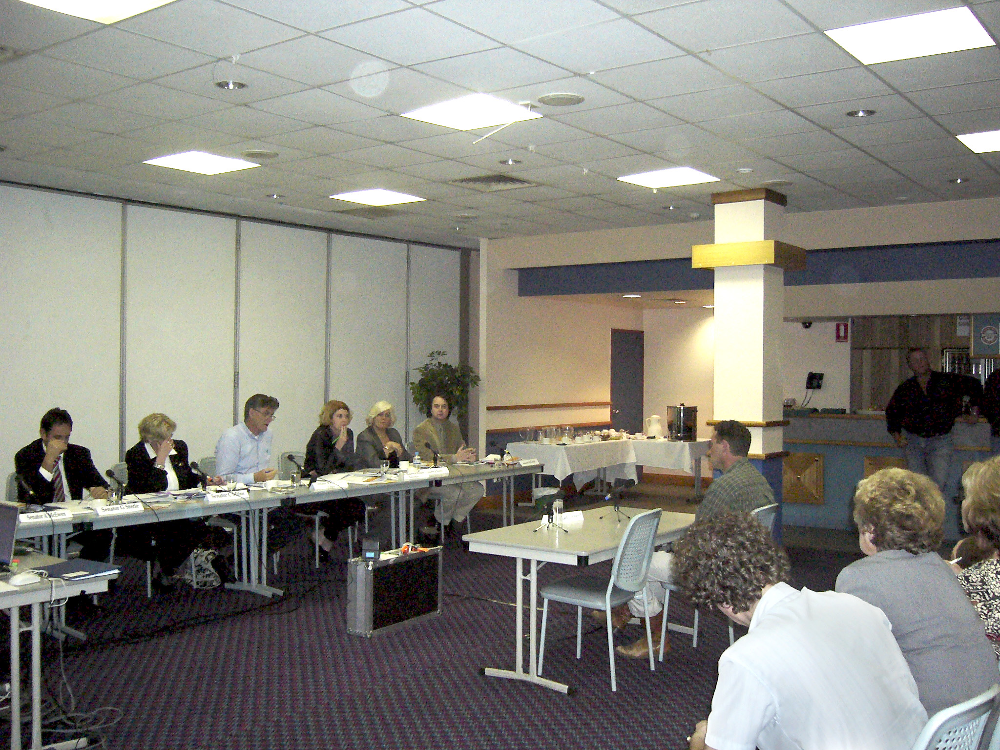 Rural and Regional Affairs and Transport Legislation Committee hearing evidence from witness Michael Benham at a public hearing in Emerald, Qld, of its inquiry into the Department of Agriculture, Fisheries and Forestry’s administration of the citrus canker outbreak, 28 July 2005. Seated L-R: Senators Glenn Sterle, Christine Milne and Bill Heffernan [Chair], Maureen Weeks [Secretary], Senators Jeannie Ferris and Julian McGauran.