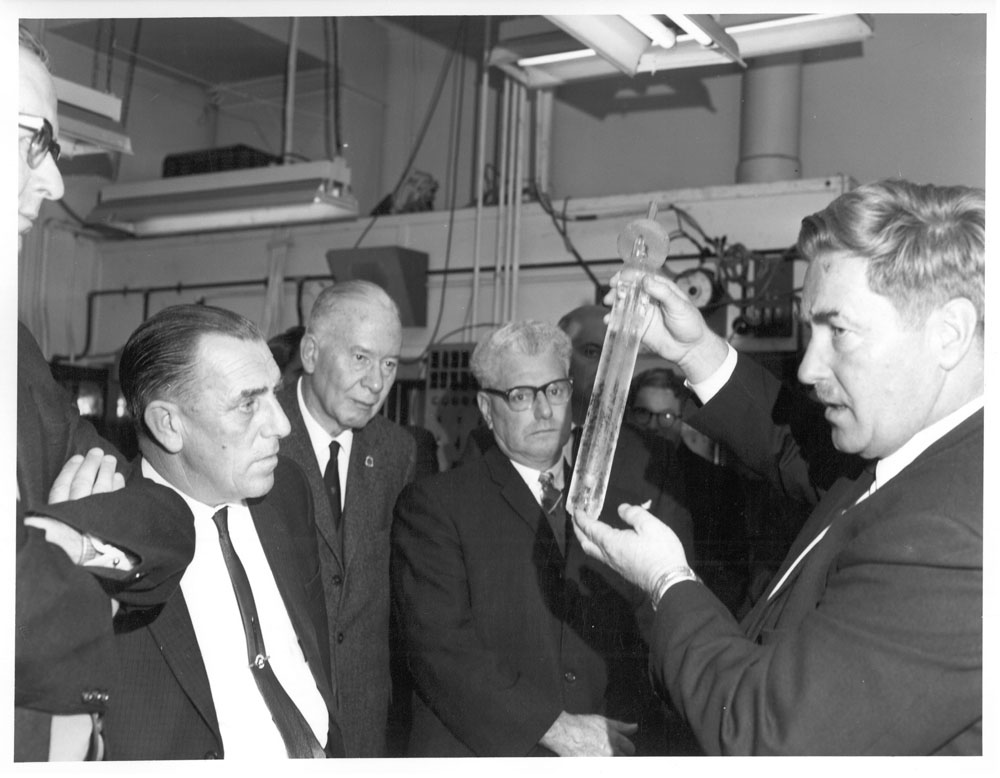 The committee's technical consultant, Alan Harper, demonstrating the use of laboratory measurement equipment to committee members at the CSIRO National Standards Laboratory, Sydney, 1967. L-R: Senators Frank McManus, George Poyser, Keith Laught [Chair] and Arnold Drury, and Alan Harper [Senior Principal Research Scientist, Division of Physics, CSIRO National Standards Laboratory].