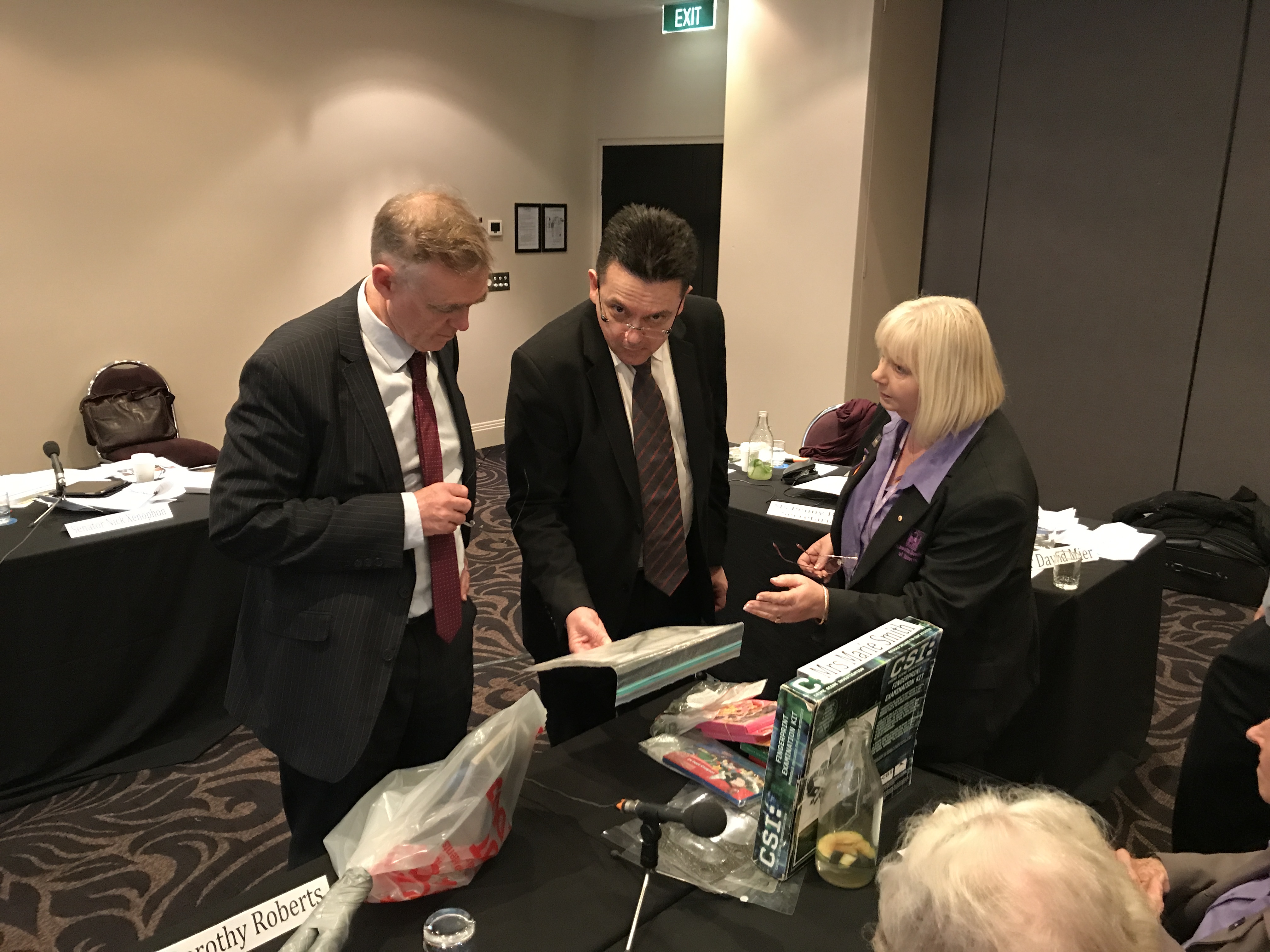 L-R: Senators Chris Ketter [Chair], Nick Xenophon and Vicki Hamilton of the Asbestos Council of Victoria examine products containing asbestos at a hearing in Melbourne, 14 July 2017.
