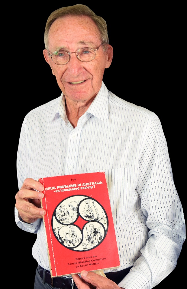 Peter Baume pictured holding his report.  Image courtesy of Foundation for Alcohol Research and Education (FARE)
