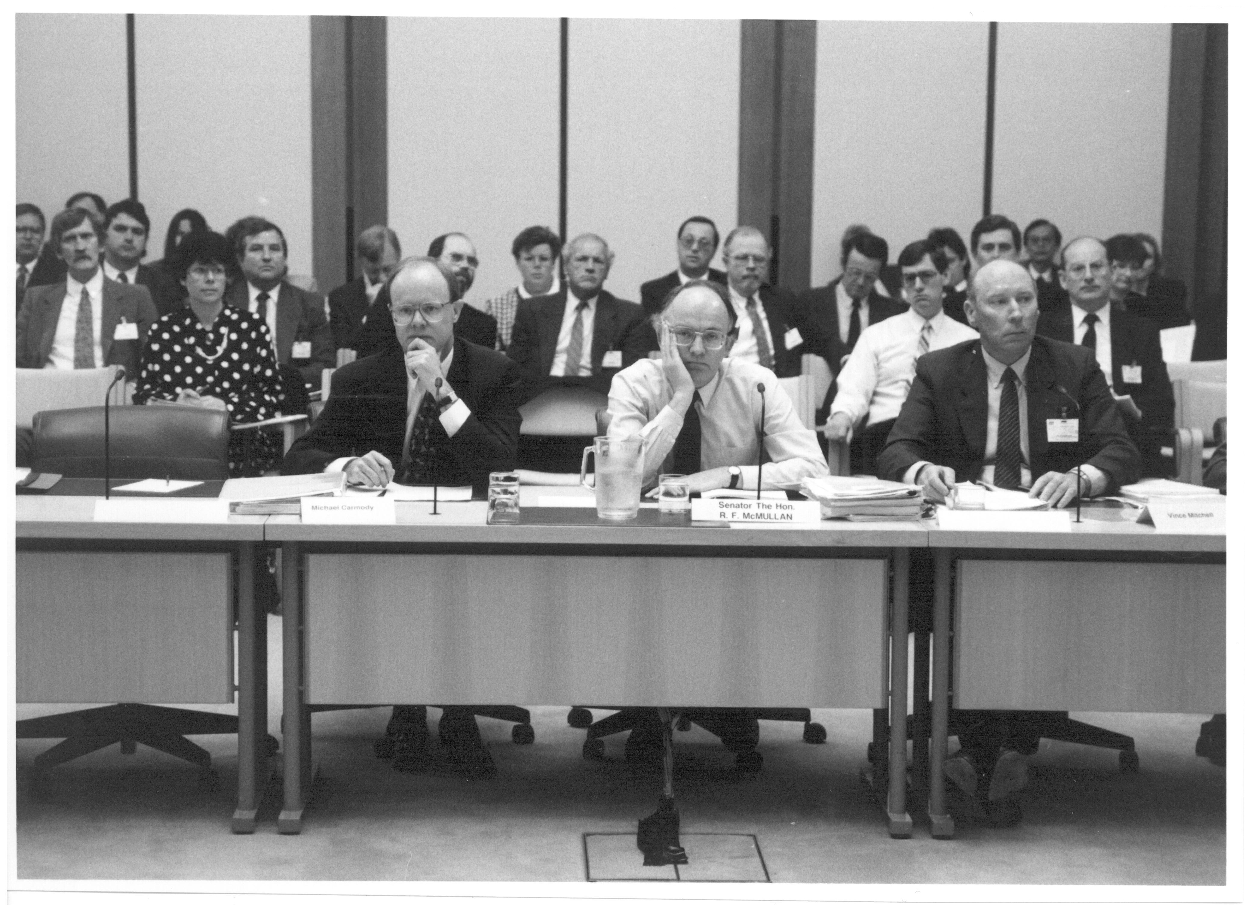 Senator the Hon Bob McMullan, Parliamentary Secretary to the Treasurer, appearing with officers from the Australian Taxation Office at supplementary budget estimates hearing, 11 October 1991. Seated L-R: Witnesses Michael Carmody [Second Commissioner of Taxation], Senator Bob McMullan [Parliamentary Secretary to the Treasurer] and Vince Mitchell [First Assistant Commissioner, Taxpayer Audit].