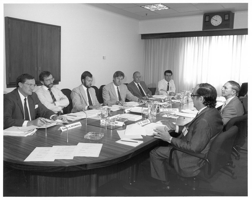 Officers from the Commonwealth Scientific and Industrial Research Organisation (CSIRO) at a public hearing of the Standing Committee on Industry and Trade, 26 March 1987. Clockwise around table from left: Senators David Brownhill and Peter Cook, Peter Keele [Secretary], Senators Bruce Childs [Chair], Warwick Parer and Jim McKiernan, Michael Game [Research Officer], witnesses Dr David Solomon [Acting Director, Institute of Industrial Technology, CSIRO] and Dr Robert Frater [Chief of the Division of Radiophysics, CSIRO].