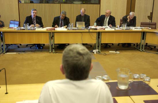 Select Committee on the Scrafton Evidence hearing, 1 September 2004. Seated facing camera L-R: Senators Andrew Bartlett and Robert Ray [Chair], Alistair Sands [Secretary], Senators George Brandis [Deputy Chair] and Alan Ferguson. Witness Michael Scrafton seated with back to camera. DPS Auspic.