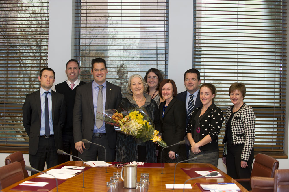 Senator Sue Boyce receiving flowers from members and staff of the Standing Committees on Community Affairs upon her retirement from the Senate, 24 June 2014. L-R: Tasman Larnach [Research Officer], Richard Grant [Principal Research Officer], Senators Zed Seselja and Sue Boyce [Chair, Legislation], Monika Sheppard [Senior Research Officer], Senators Rachel Siewert [Deputy Chair, Legislation] and Dean Smith, Carol Stewart [Administrative Officer] and Jeanette Radcliffe [Secretary]. DPS Auspic.