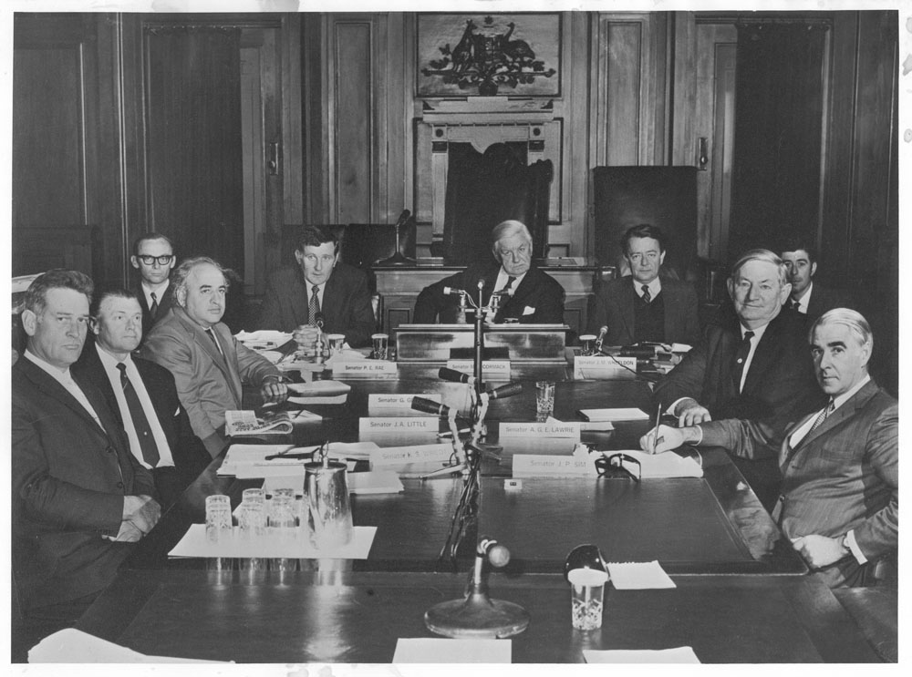 Select Committee on Securities and Exchange in session in the Senate Chamber of the Provisional Parliament House, May 1971. L-R: Senators Ken Wriedt and Jack Little, J.M. Collins [Research Officer], Senators George Georges, Peter Rae, Magnus Cormack [Chair], John Wheeldon and Ellis Lawrie, Don Whitbread [Secretary] (obscured) and Senator Peter Sim.