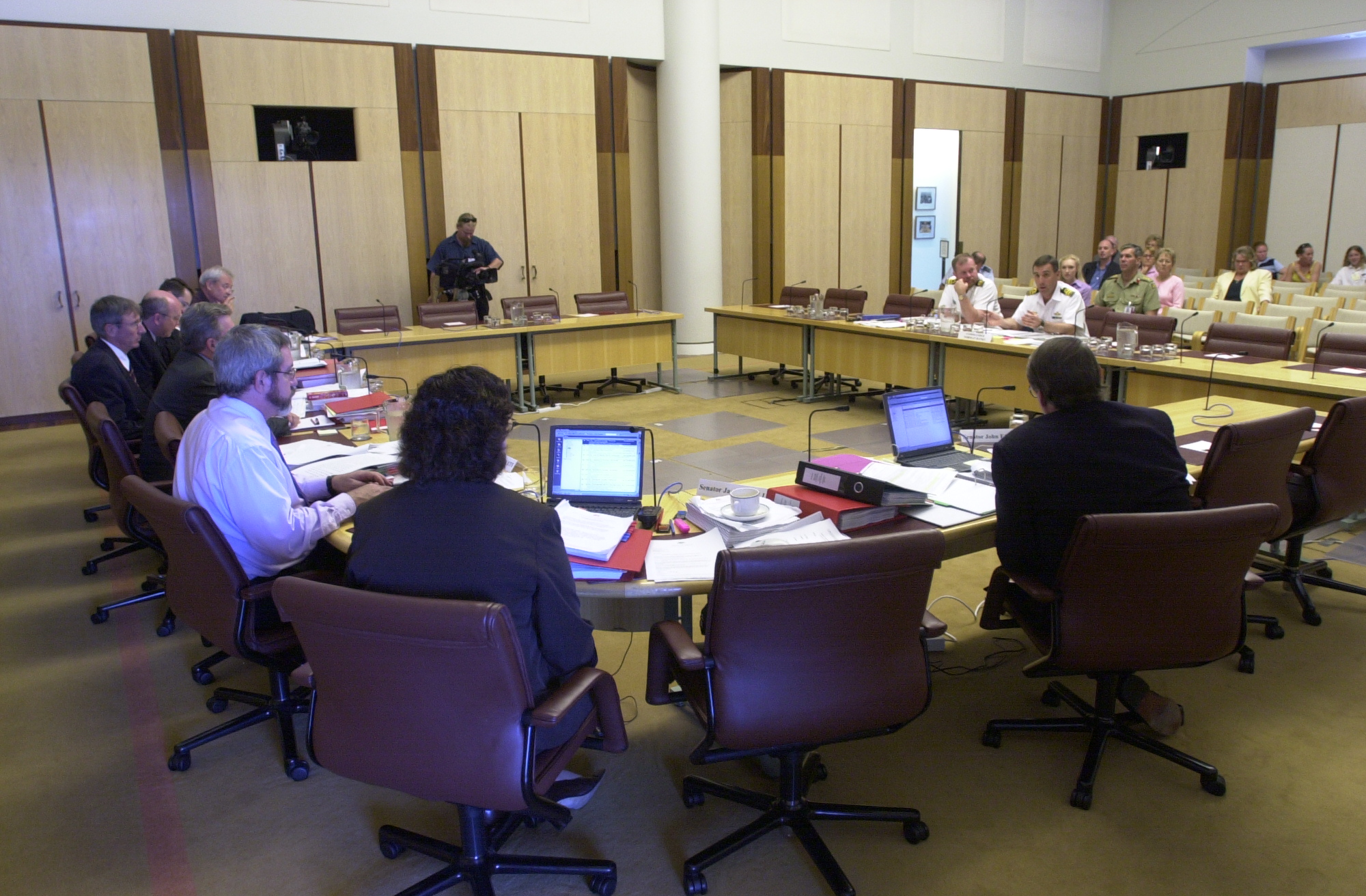 Select Committee on a Certain Maritime Incident hearing evidence from witness Commander Norman Banks at a public hearing, 26 March 2002. Seated at curved table, farthest to closest: Senators Alan Ferguson, Brett Mason and George Brandis [Deputy Chair], Brenton Holmes [Secretary], Senators Peter Cook [Chair], Andrew Bartlett, Jacinta Collins and John Faulkner. DPS Auspic.