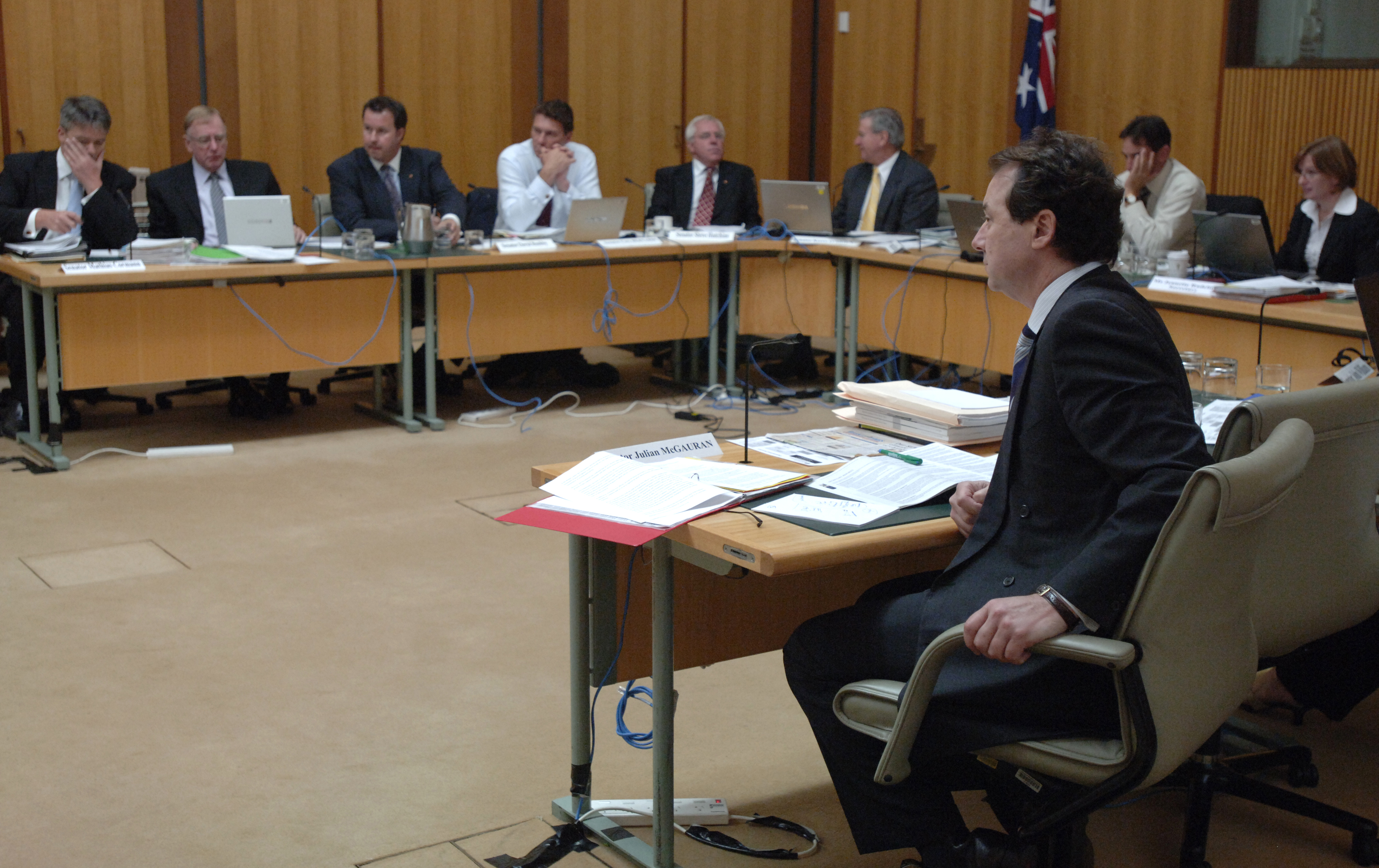 Members of the Standing Committee on Rural and Regional Affairs and Transport at an additional estimates hearing, 24 February 2009. L-R: Senators Mathias Cormann, Ian Macdonald, David Bushby, Cory Bernardi, Steve Hutchins, Kerry O'Brien and Glenn Sterle [Chair], and Jeanette Radcliffe [Secretary]. Senator Julian McGauran in foreground. DPS Auspic.
